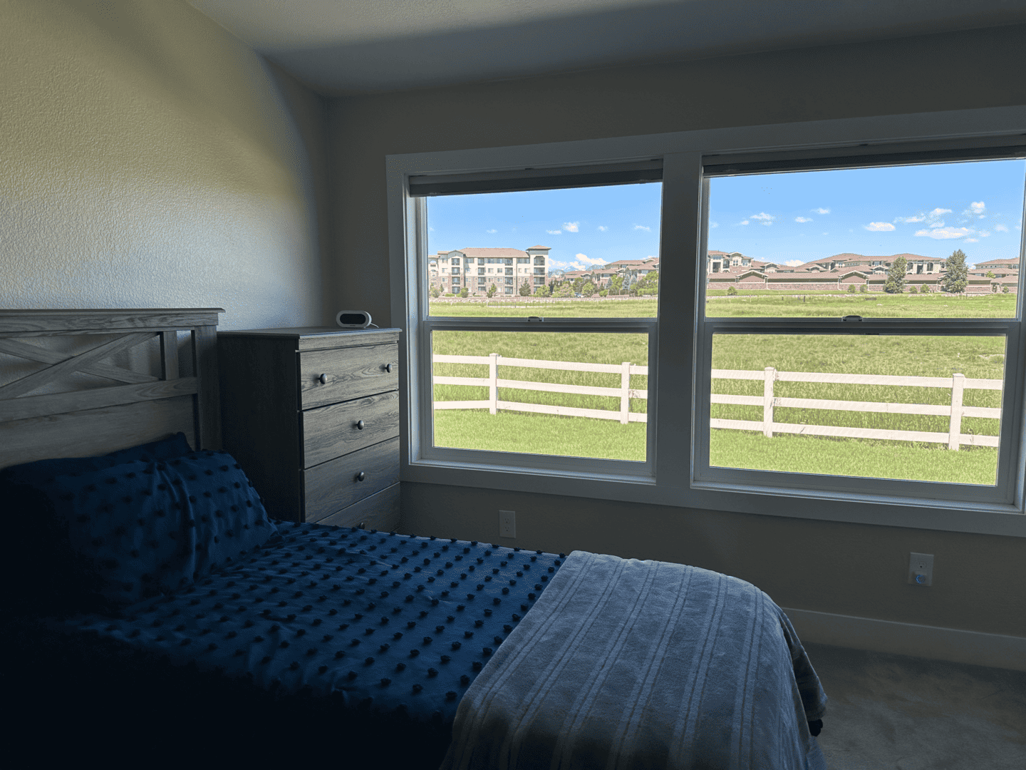 bed with dresser and window with view of ranch