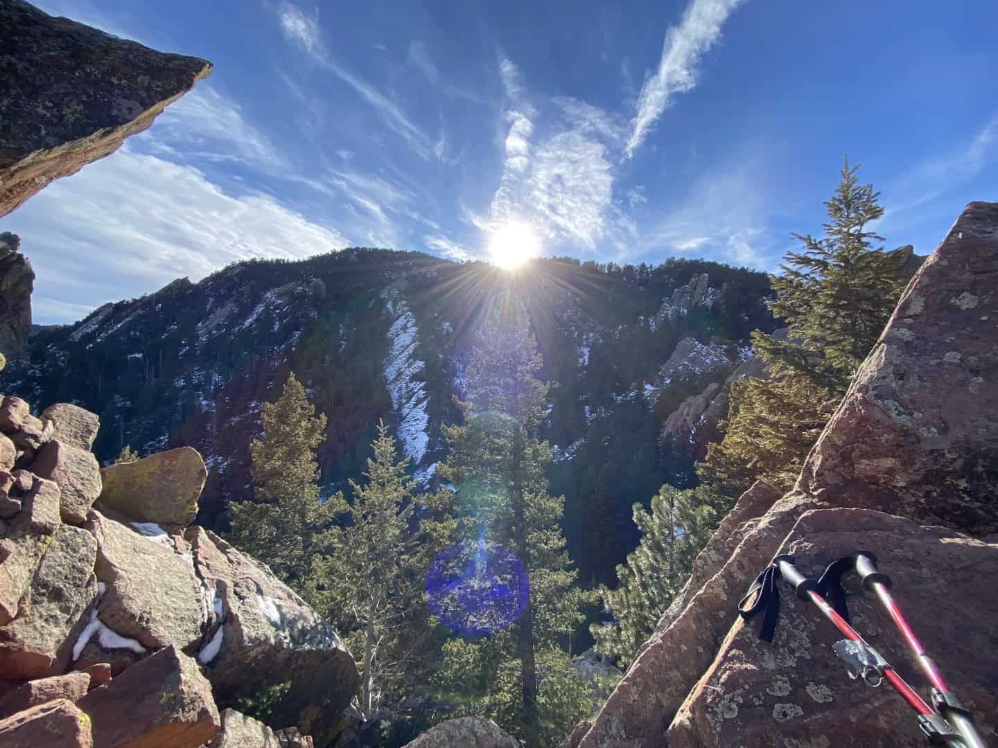 sun behind mountain in Colorado with trekking poles in foreground