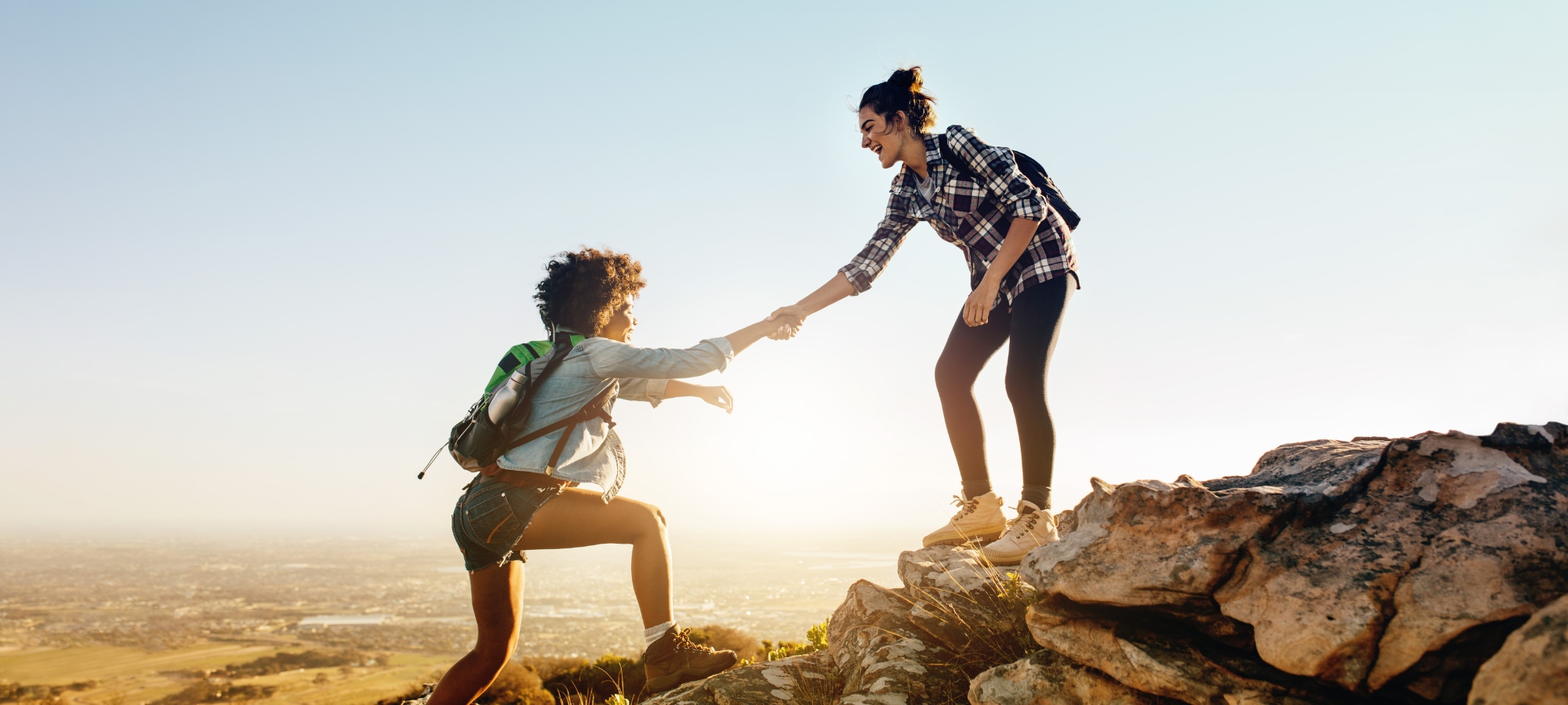 Two women assist one another on A holistic therapy hiking expedition with a focus on women and addiction.